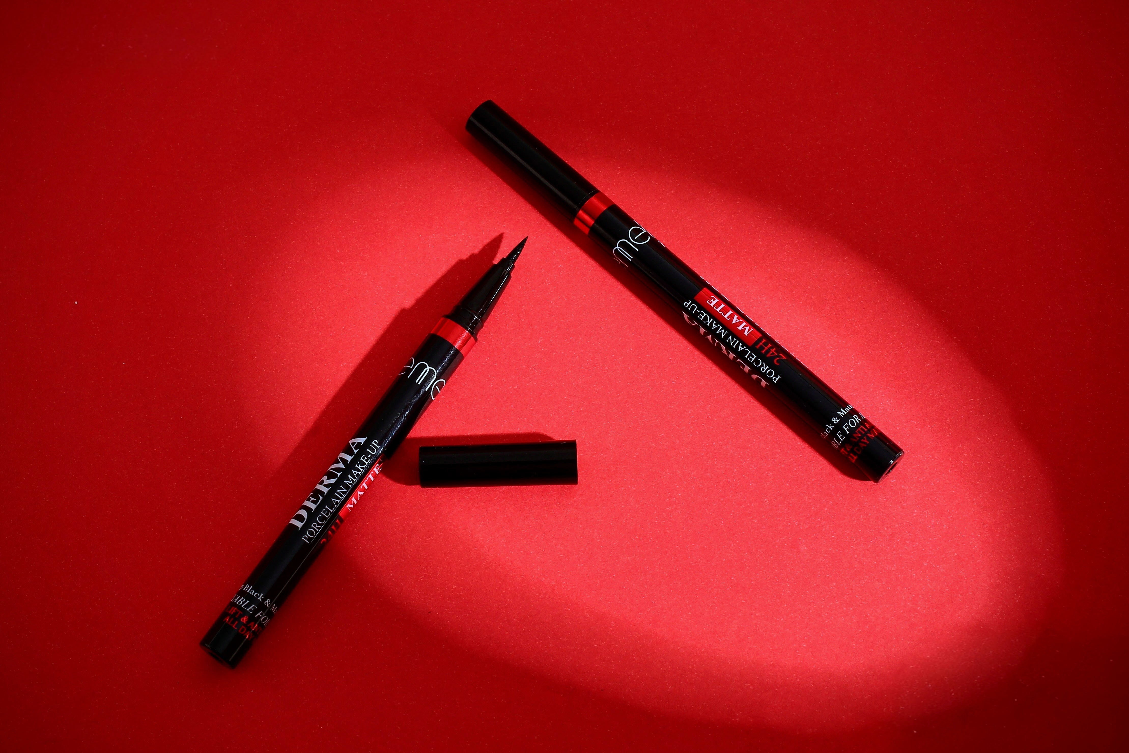 Black liquid eyeliner with applicator on red background